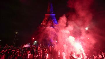 Paris Saint-Germain's supporters light smoke flares in front of The Eiffel Tower illuminated in the colours of the PSG in Paris on May 31, 2025, during celebrations following their 5-0 victory in the UEFA Champions League final football match between Paris Saint-Germain (PSG) and Inter Milan held in Munich. (Photo by Thibaud MORITZ / AFP)
